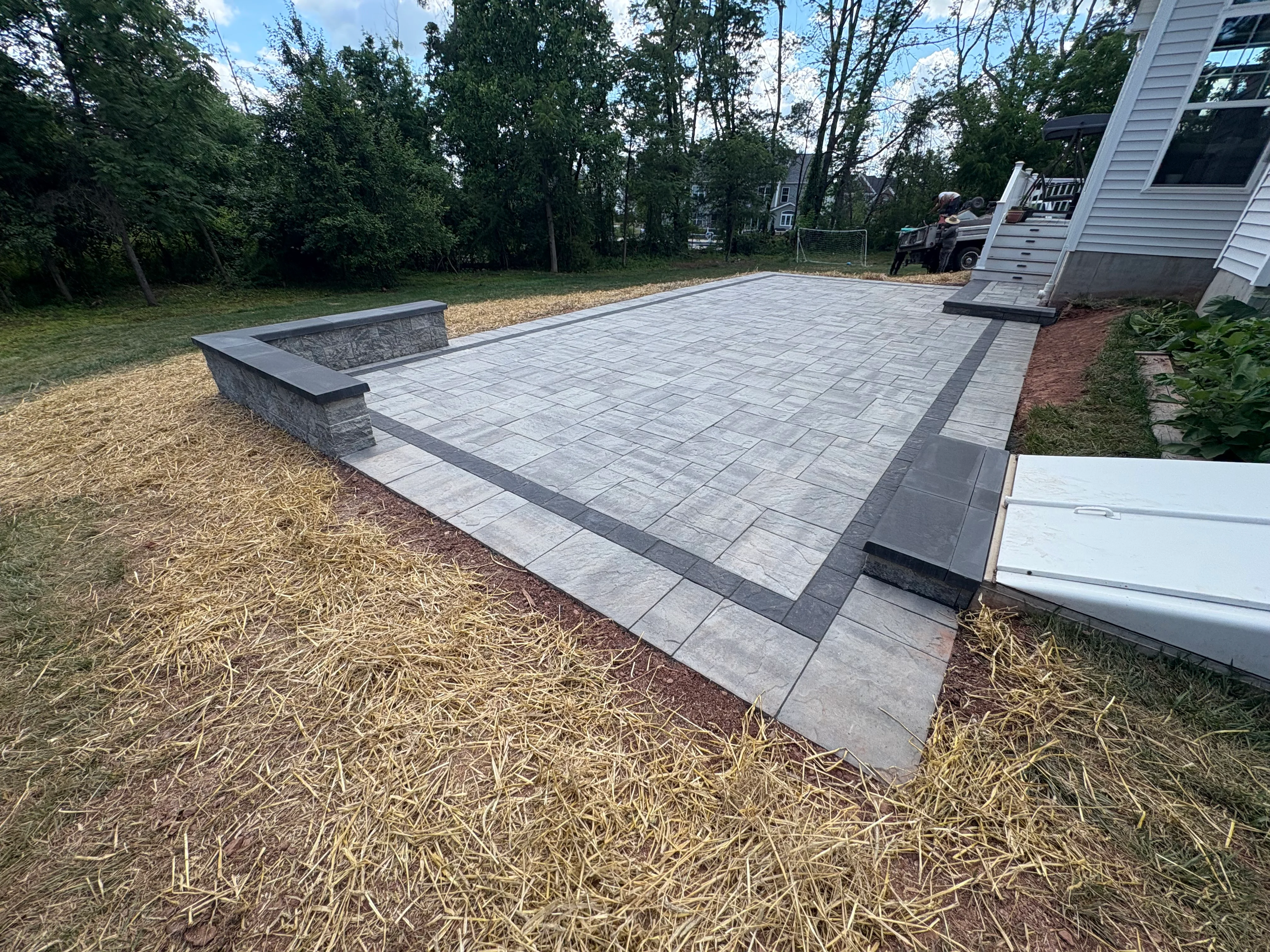 Gray permeable pavers with dark border stripe and integrated stone seating wall